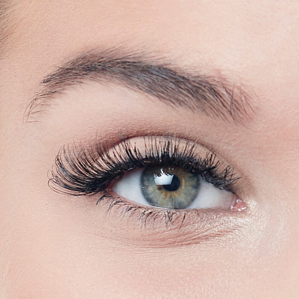 Close-up image of a human eye showcasing long, voluminous eyelashes and a striking green iris, emphasizing eye beauty and makeup.