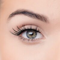 Close-up image of a woman's eye showcasing long eyelashes and a striking iris, highlighting eye beauty and makeup.