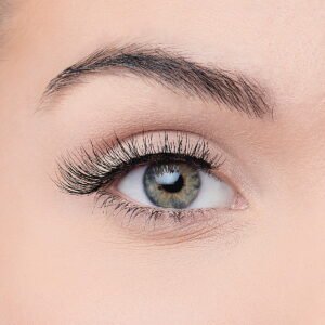 Close-up image of a human eye showcasing long eyelashes and a natural iris color, highlighting eye beauty and makeup.