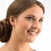 Close-up of a smiling woman wearing elegant pearl earrings and a silver necklace, showcasing jewelry style and beauty.