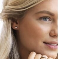 Close-up of a woman wearing elegant diamond stud earrings, showcasing a classic jewelry design that enhances beauty and style.