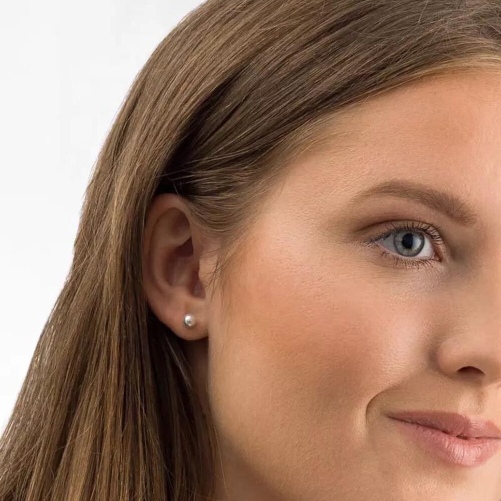 Close-up of a woman wearing elegant pearl earrings, showcasing a classic and timeless jewelry piece suitable for various occasions.