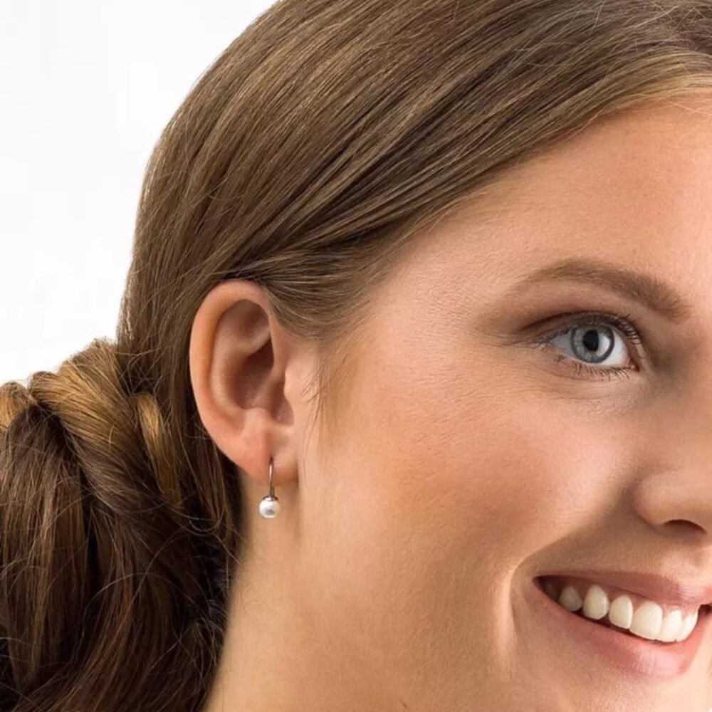 Close-up of a woman wearing elegant silver pearl earrings, showcasing a classic design that enhances any outfit with a touch of sophistication.