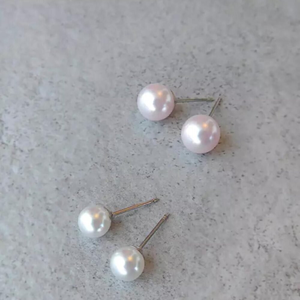 Set of elegant pearl stud earrings featuring pink and white pearls on silver posts, perfect for any occasion.