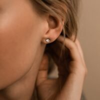 Close-up of a woman's ear showcasing a sparkling diamond stud earring, highlighting its brilliance and elegance.