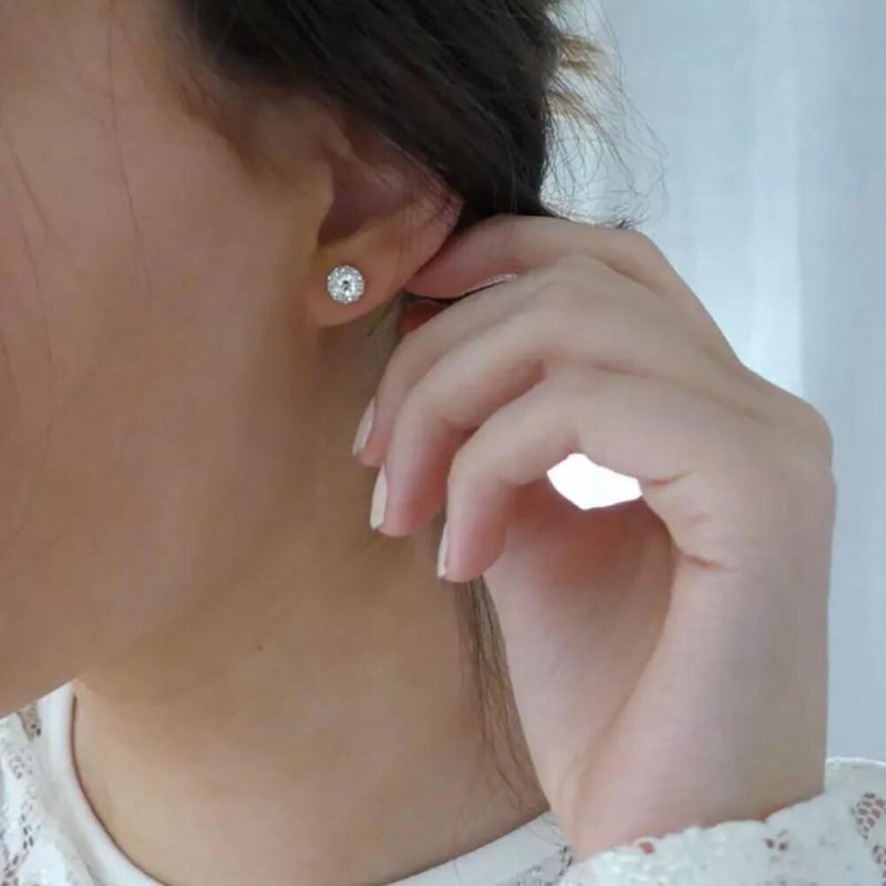 Close-up of a woman wearing elegant silver stud earrings with a sparkling design, showcasing a classic jewelry style.