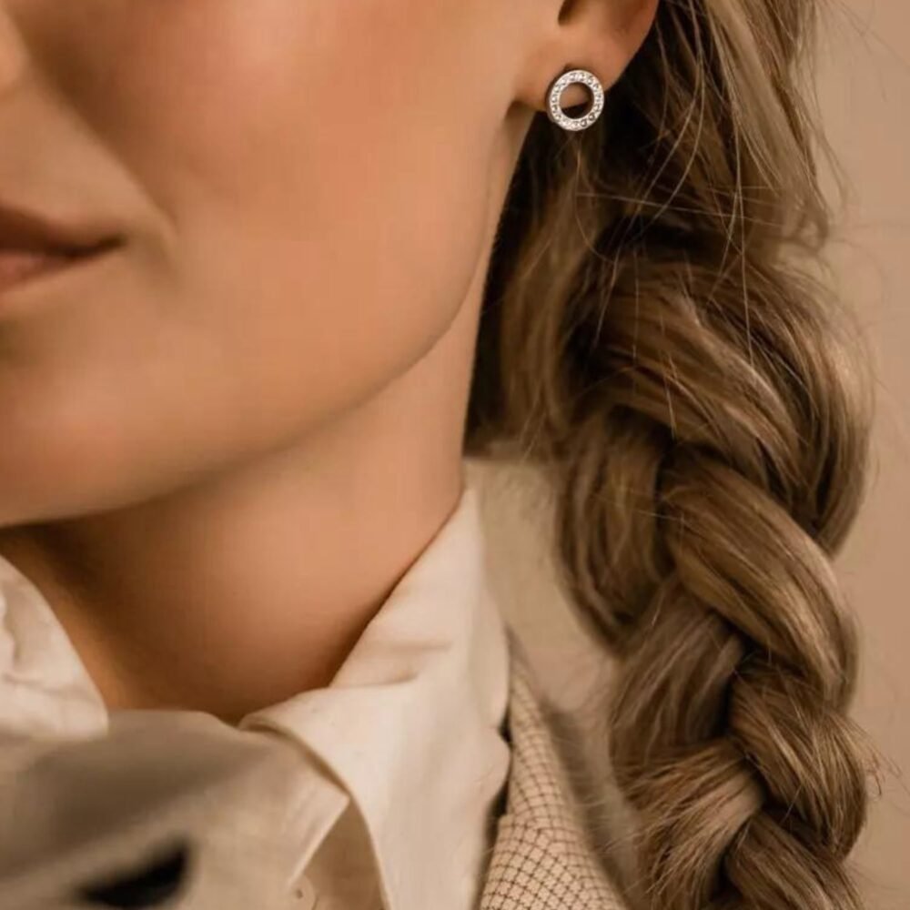 Close-up of a woman wearing elegant silver hoop earrings adorned with diamonds, showcasing a sophisticated style.