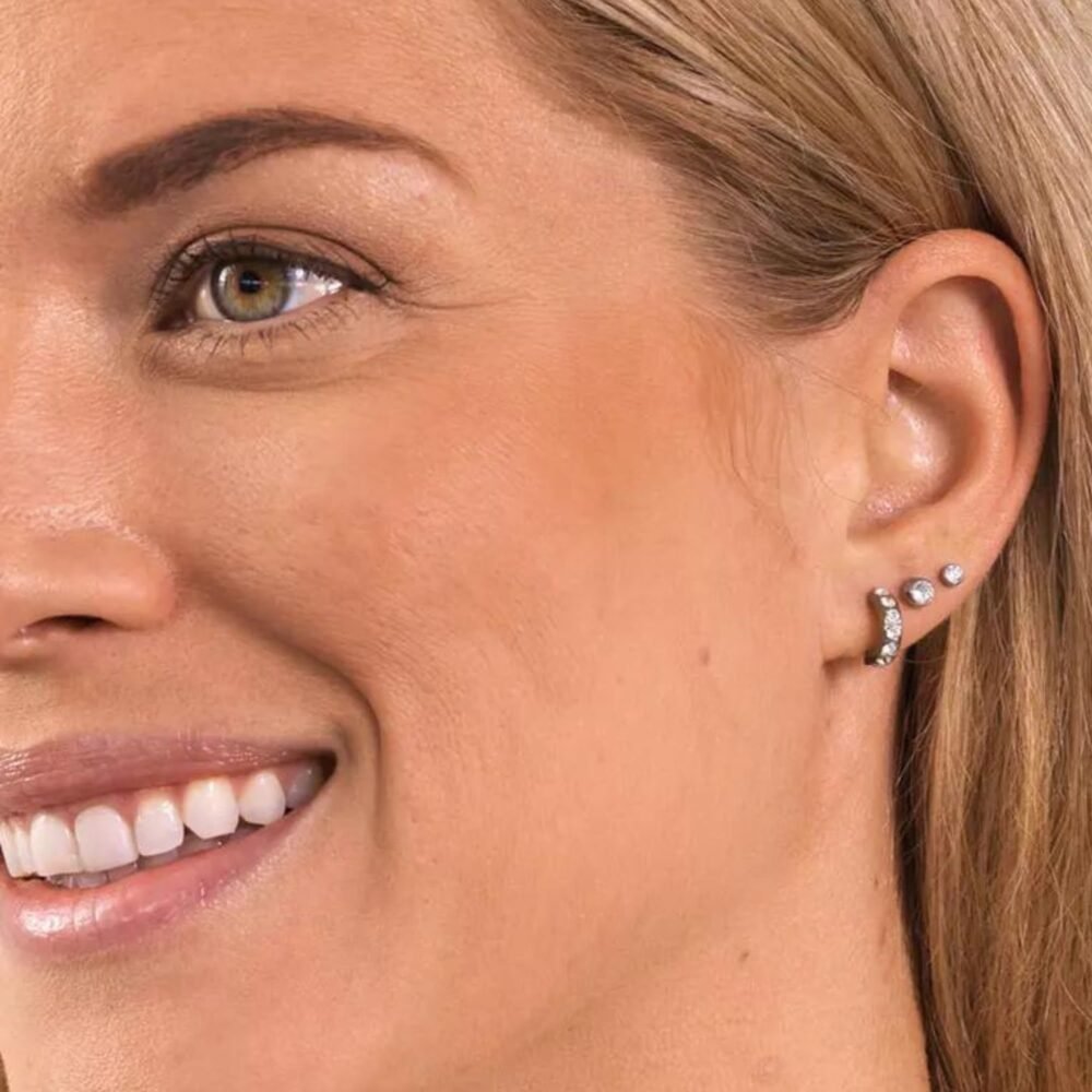 Stylish woman wearing a set of elegant stud earrings featuring sparkling stones, showcasing a modern jewelry design.