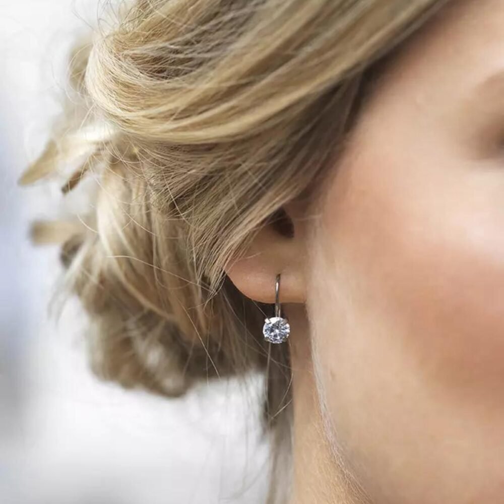 Close-up of a woman wearing elegant silver hoop earrings featuring a sparkling gemstone, showcasing modern jewelry design.