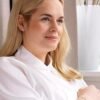 A woman with blonde hair and a white blouse, showcasing a serene expression and subtle jewelry, ideal for lifestyle and beauty contexts.