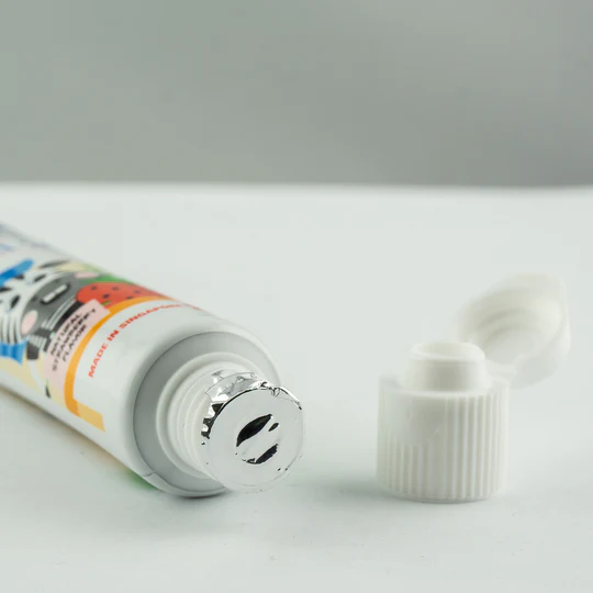 Colorful toothpaste tube with a white cap, featuring a playful design and a silver nozzle, ideal for oral care.