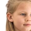 A young girl with light brown hair wearing pink flower stud earrings, showcasing a delicate and charming accessory for children.