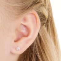 Close-up of a woman's ear showcasing elegant diamond flower stud earrings, perfect for adding a touch of sparkle to any outfit.