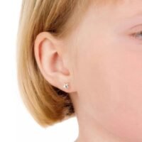 Children's silver star earrings displayed on a young girl's ear, showcasing a simple yet elegant design for kids.