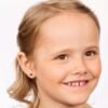 A young girl wearing star-shaped earrings, showcasing a joyful expression and light brown hair, ideal for children's accessories.