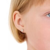 Close-up of a child's ear featuring a small flower stud earring in silver, showcasing a delicate design suitable for young wearers.