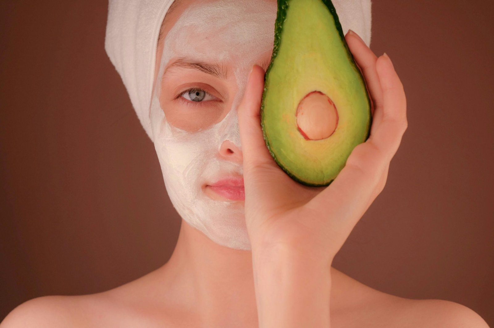 skin care treatment ..woman with white face mask holding green fruit